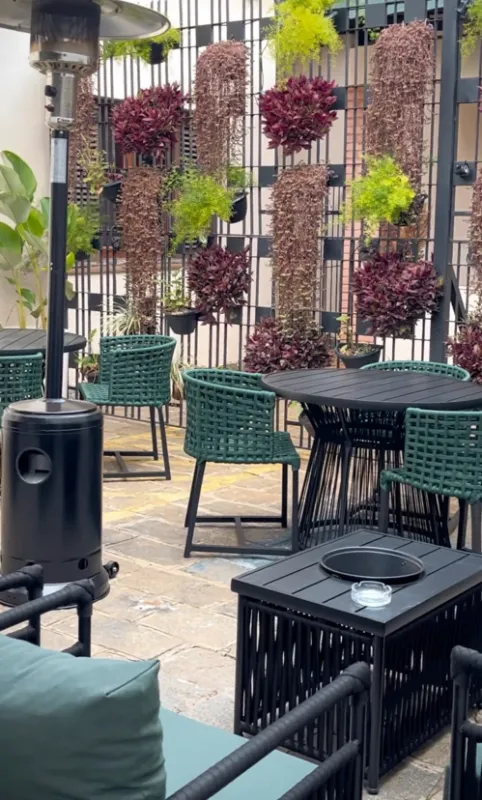 Varanda externa da Casa Petri com mesas, cadeiras e plantas em ambiente aconchegante